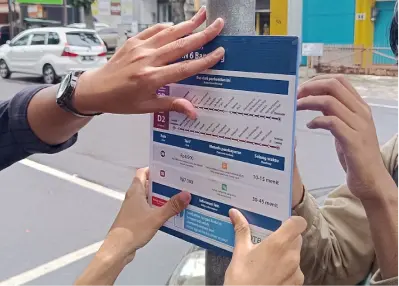 A photo of bus stop signage installation, one of Transport for Bandung's effort.